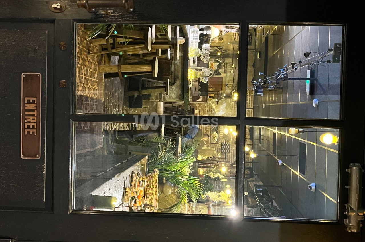 Porte vitrée donnant sur l'intérieur d'un restaurant avec des tables, des chaises et une décoration chaleureuse.