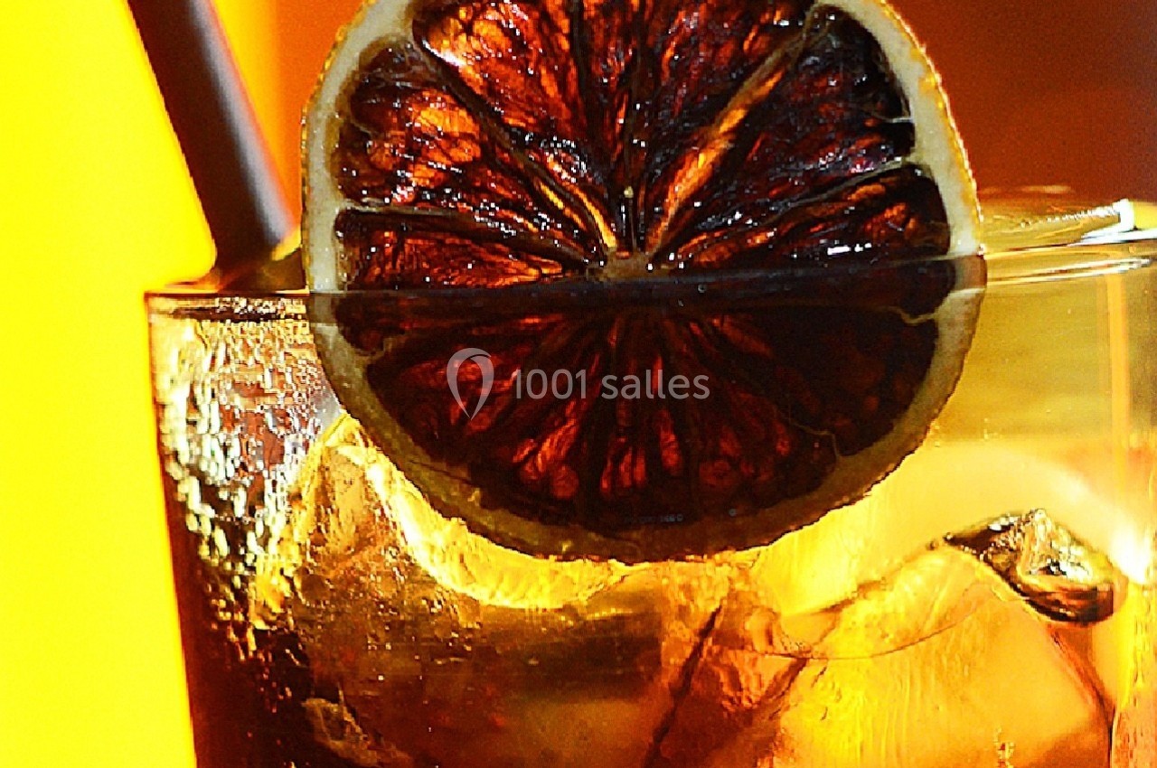 Verre de boisson glacée avec une rondelle d'orange séchée en garniture, éclairé par une lumière chaude.