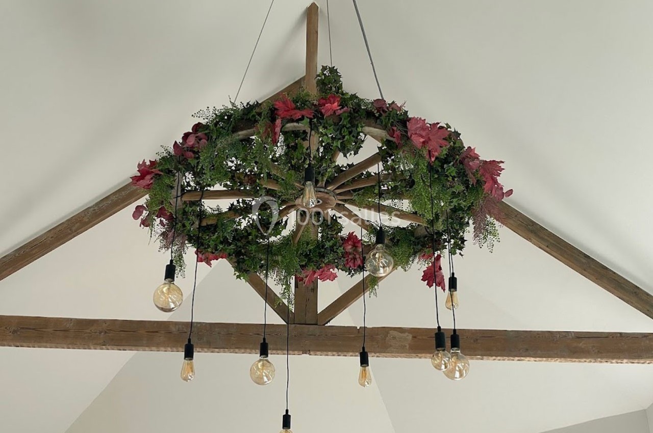 Suspension décorative en bois ornée de feuillage vert et rouge, avec des ampoules suspendues dans un plafond en poutres…