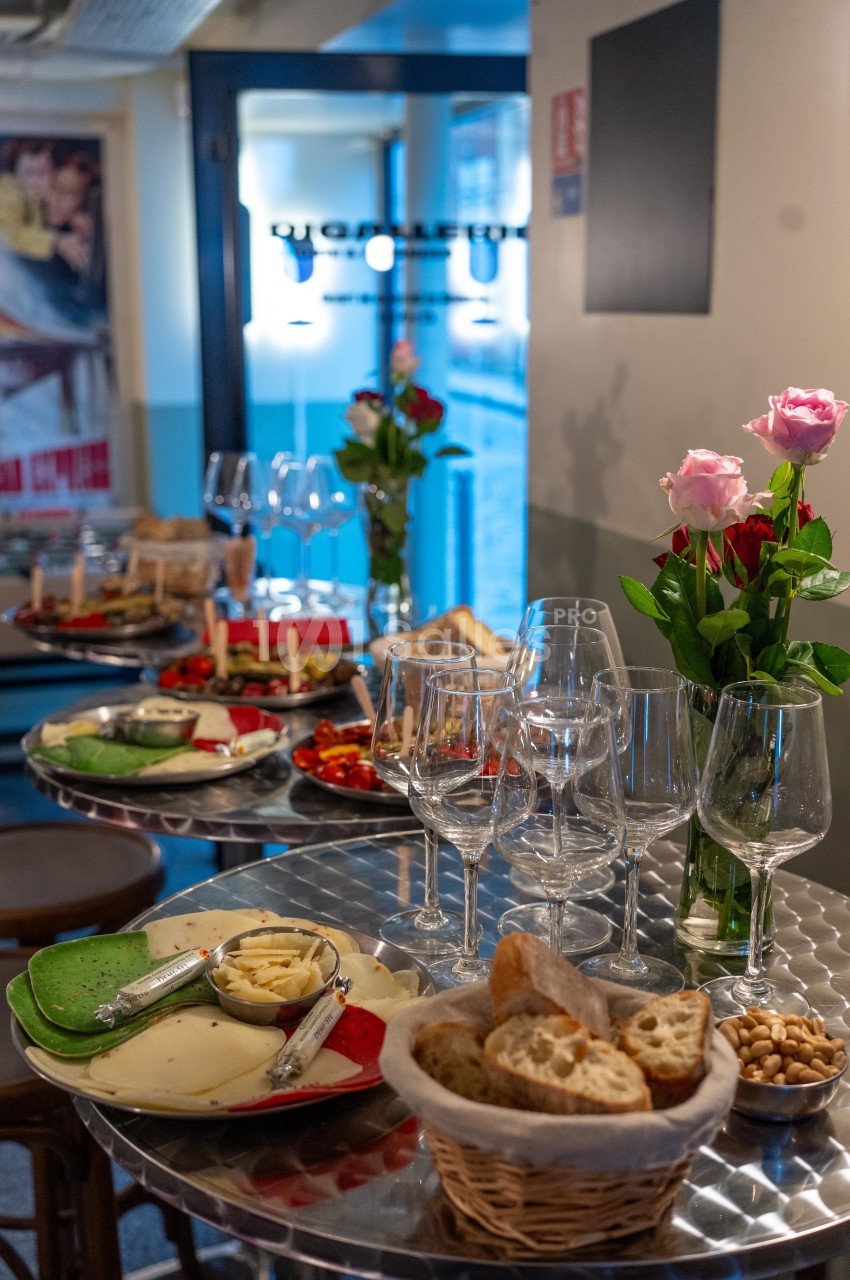 Tables dressées avec des assiettes de fromages, pain, verres à vin et décorations florales dans un cadre convivial.