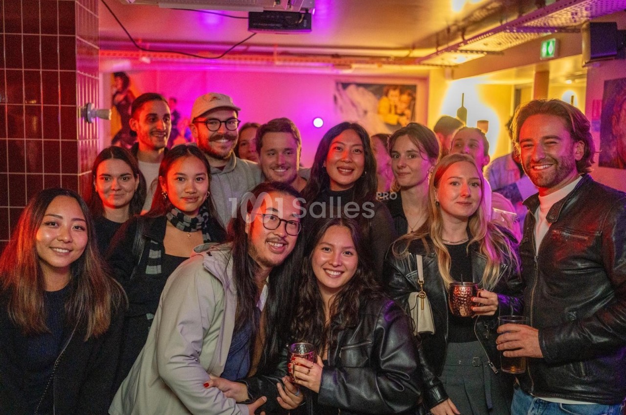 Groupe de personnes souriantes posant ensemble dans un espace intérieur avec éclairage coloré.
