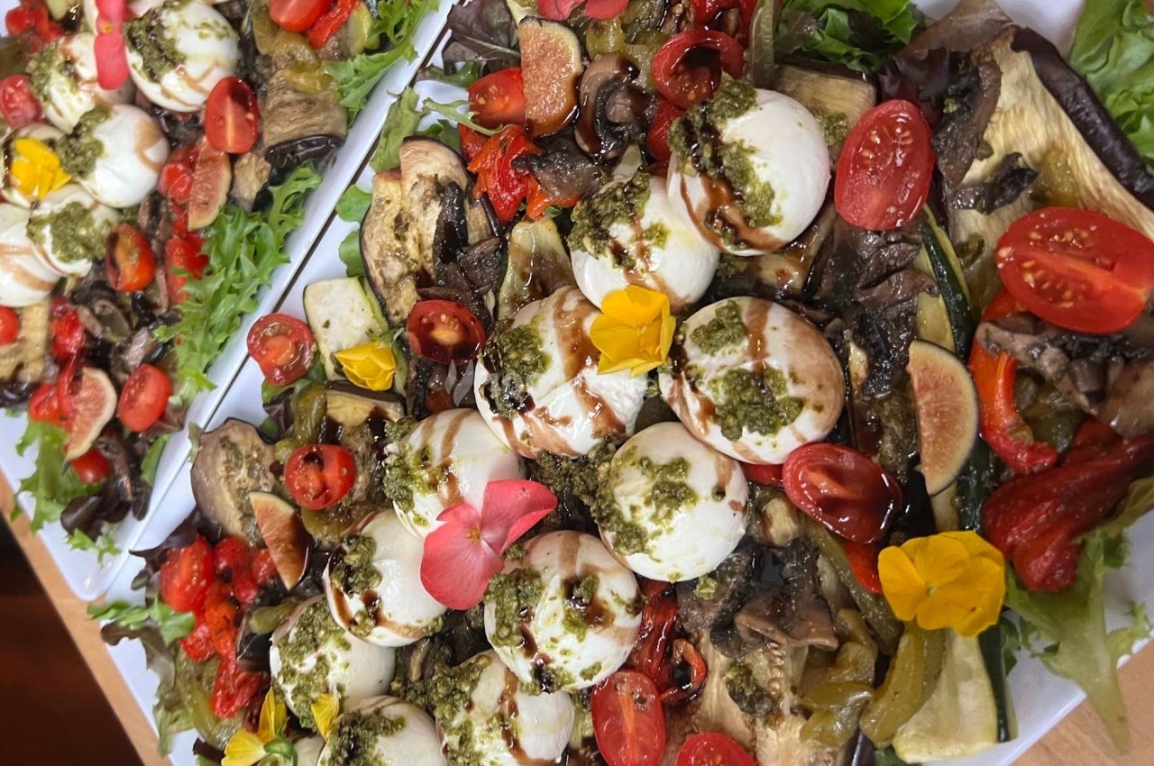 Assiette colorée composée de légumes grillés, tomates cerises, mozzarella, pesto, figues et fleurs comestibles.