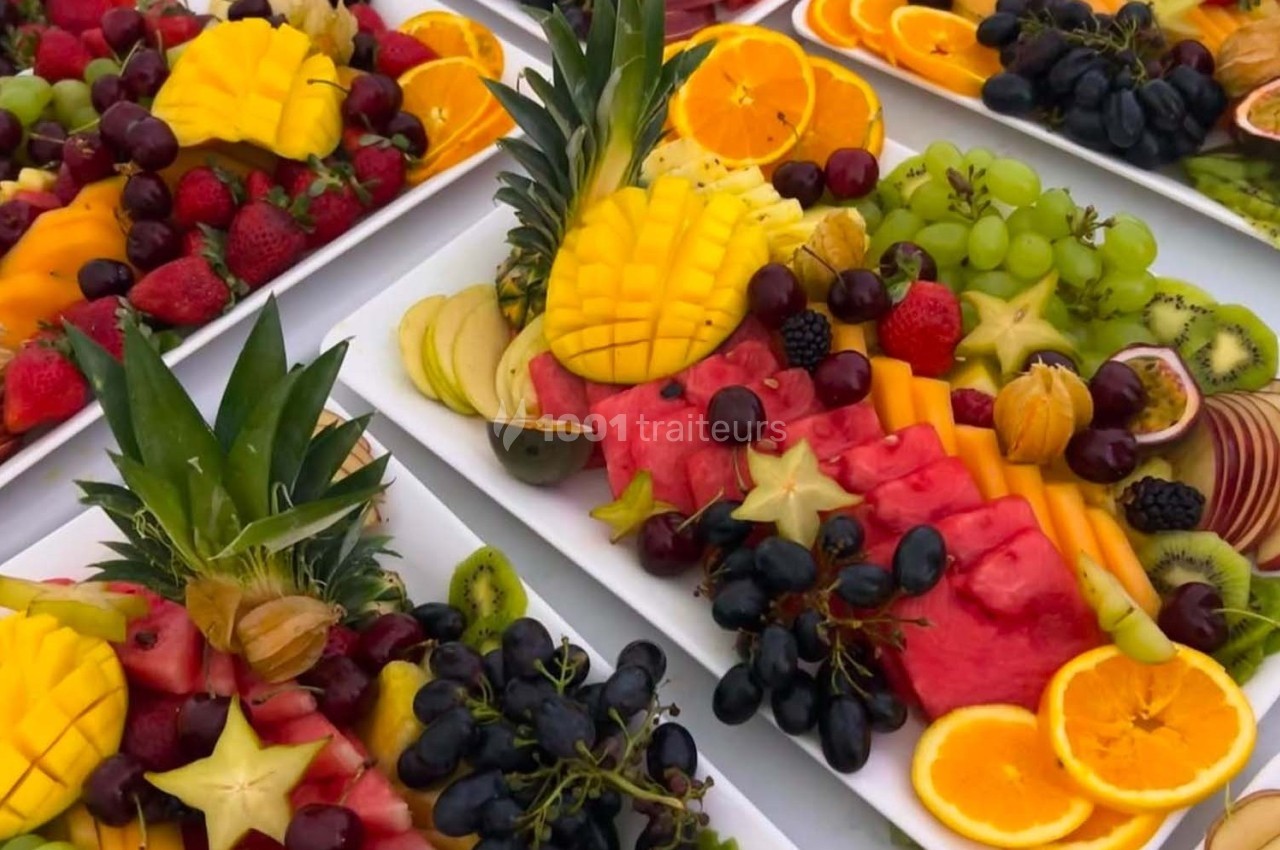 Plateaux de fruits variés comprenant pastèque, ananas, raisins, oranges, kiwis, fraises et autres fruits frais.