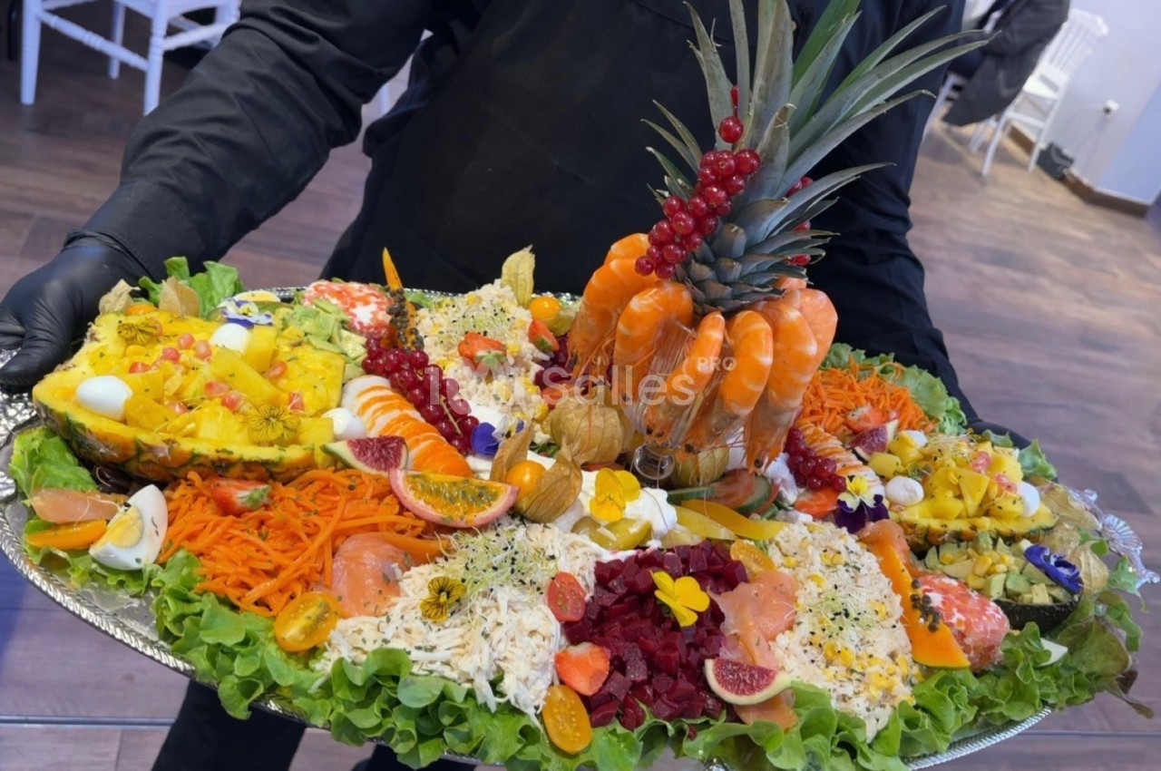 Plateau de fruits de mer et crudités décoré avec des crevettes, ananas, légumes variés et fruits colorés.