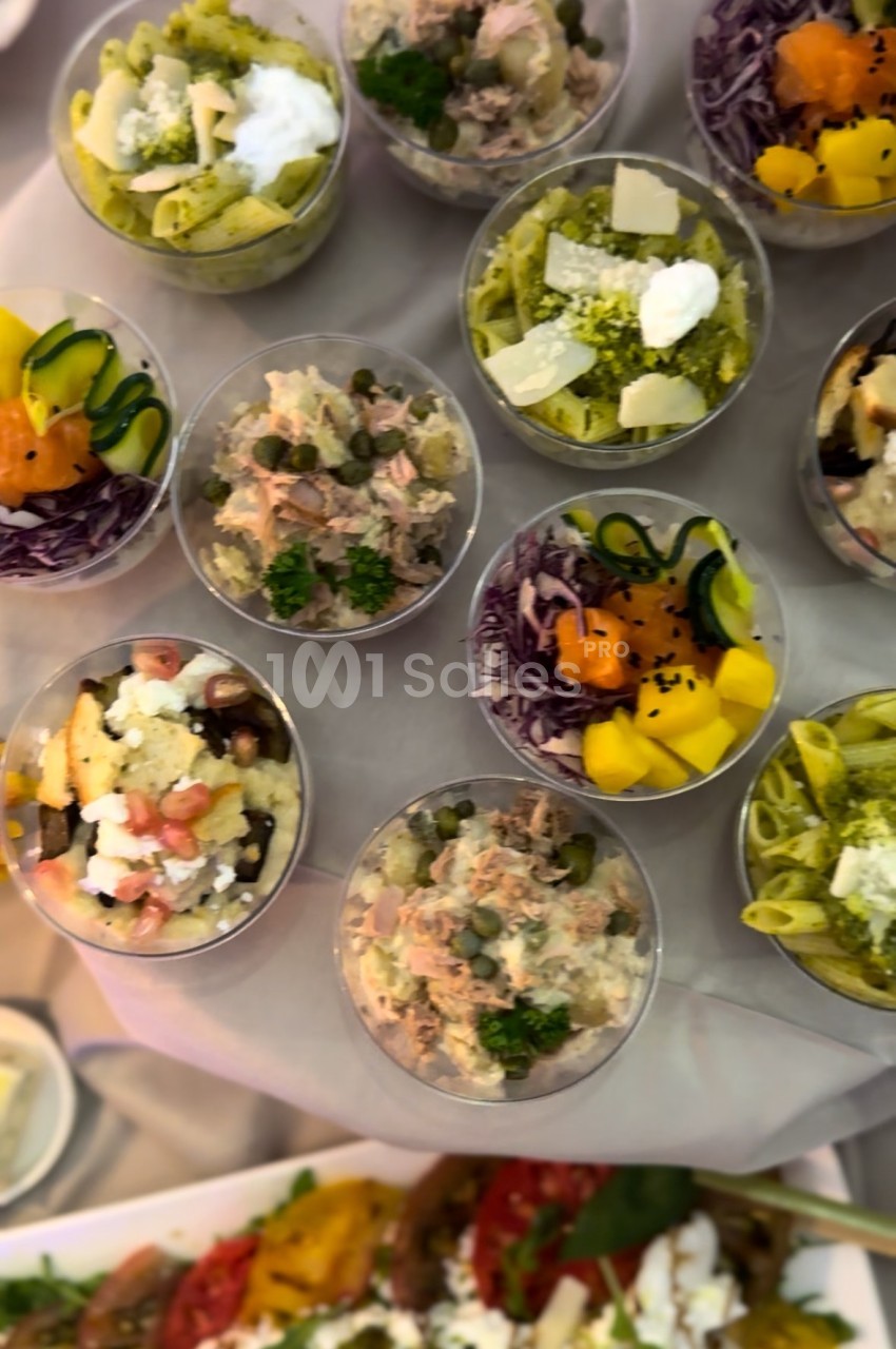 Assortiment de verrines colorées contenant des salades variées avec légumes, fromages et herbes fraîches.