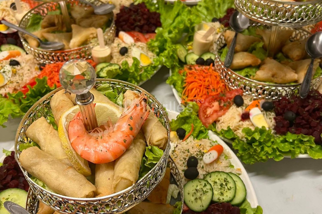 Plateaux garnis de rouleaux de printemps, crevettes, légumes frais et sauces, présentés sur des supports argentés.