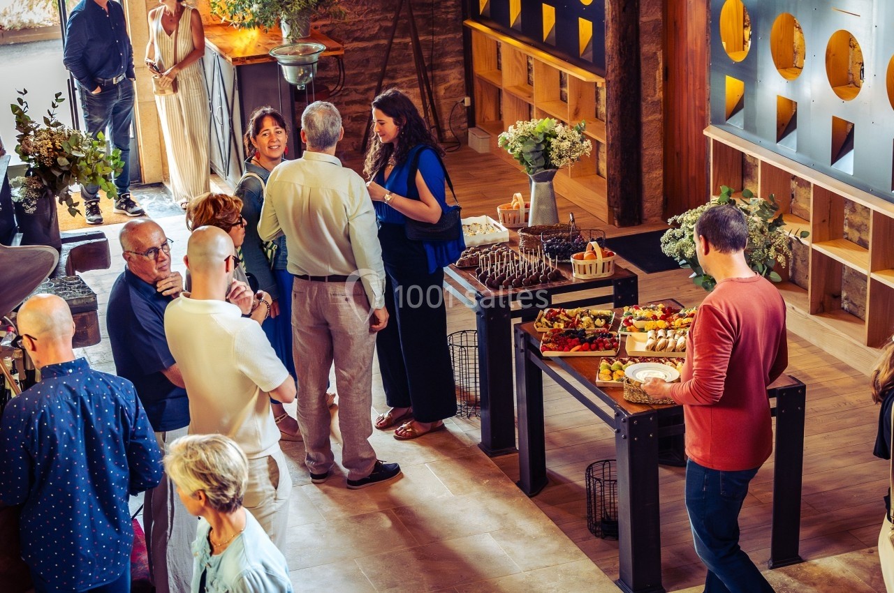 Des personnes discutent et se servent à un buffet dans une salle chaleureuse avec une décoration en bois et des fleurs.