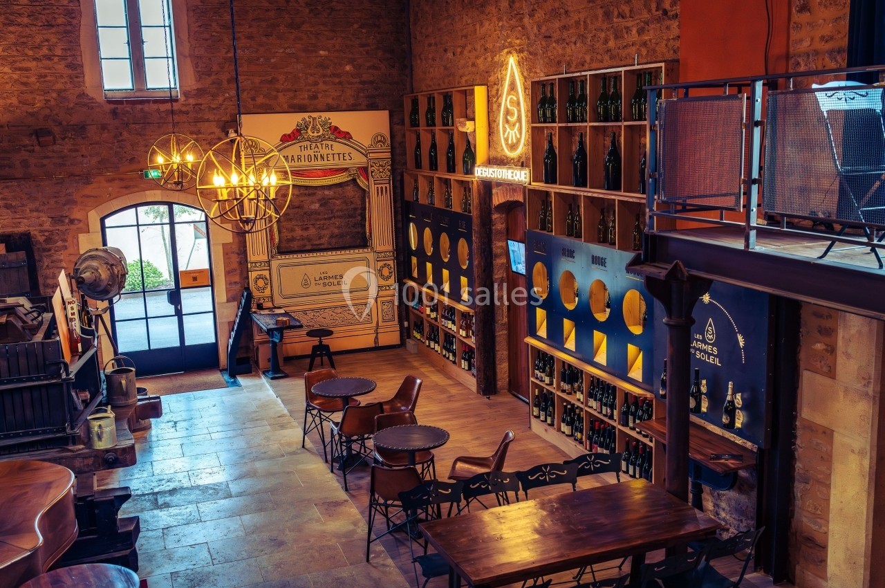 Salle intérieure d'une brasserie artisanale avec tables en bois, étagères de bouteilles et décorations lumineuses.