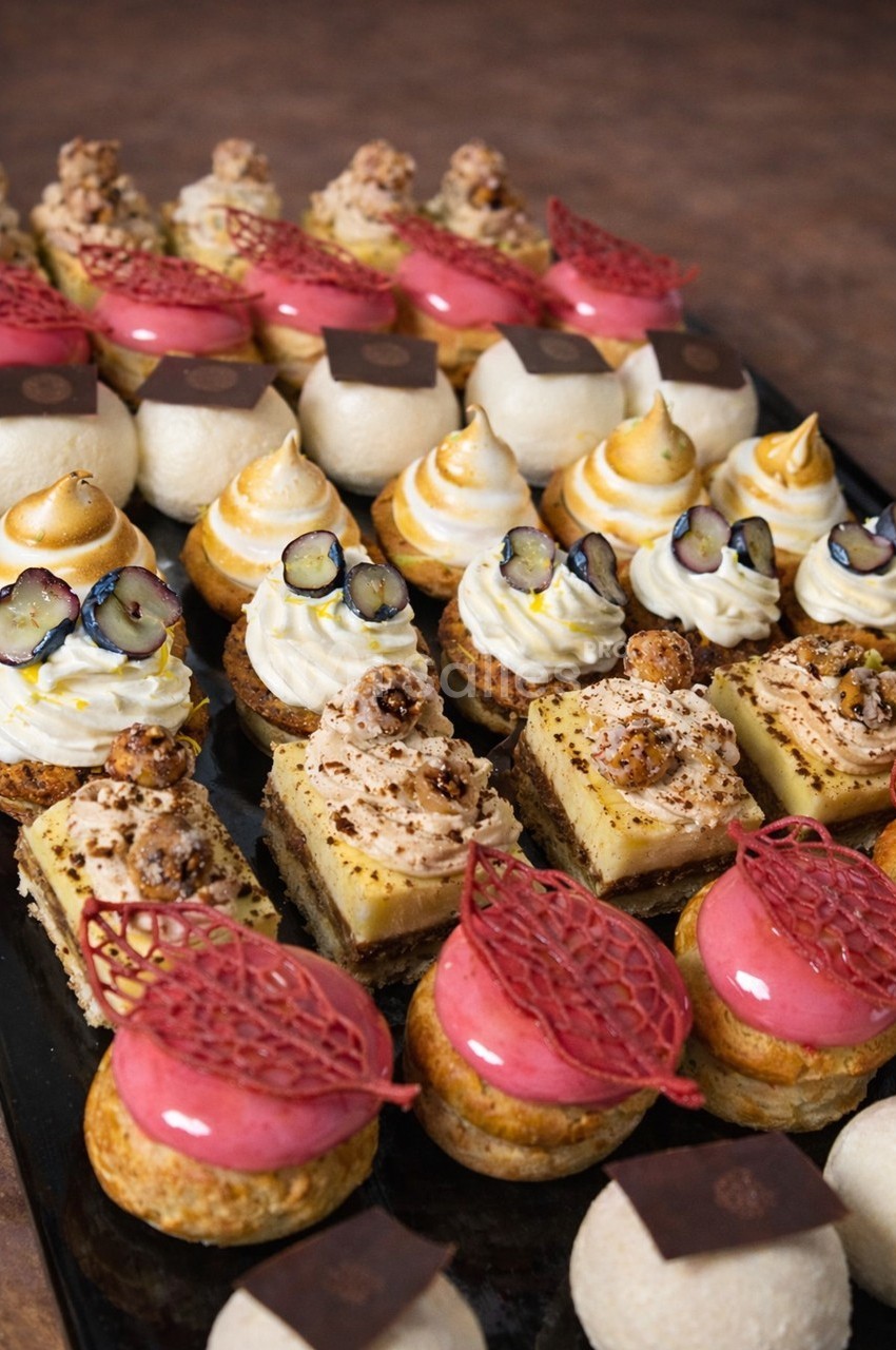 Plateau de pâtisseries variées comprenant entremets, choux garnis, tartelettes et desserts décorés de fruits et crèmes.