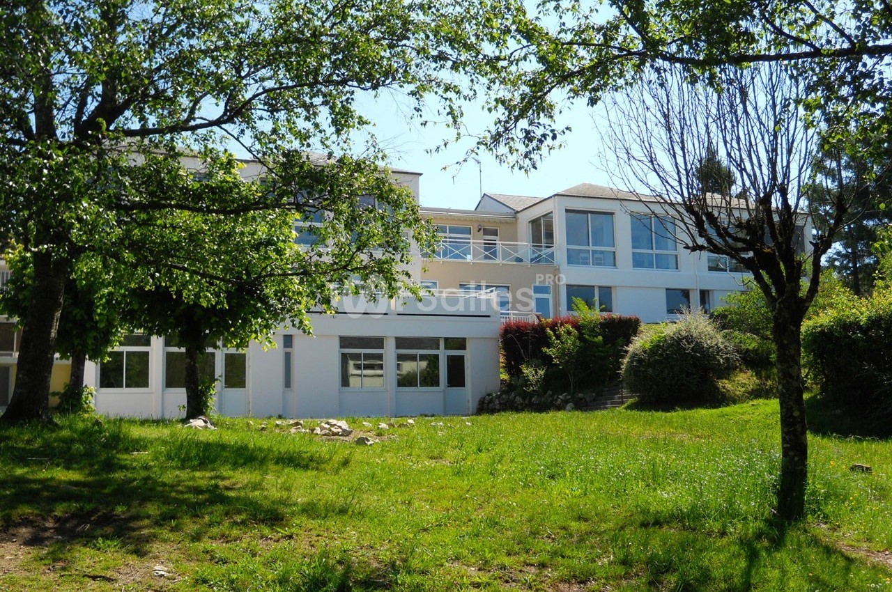 Bâtiment moderne à deux étages entouré d'arbres et de pelouse sous un ciel dégagé.