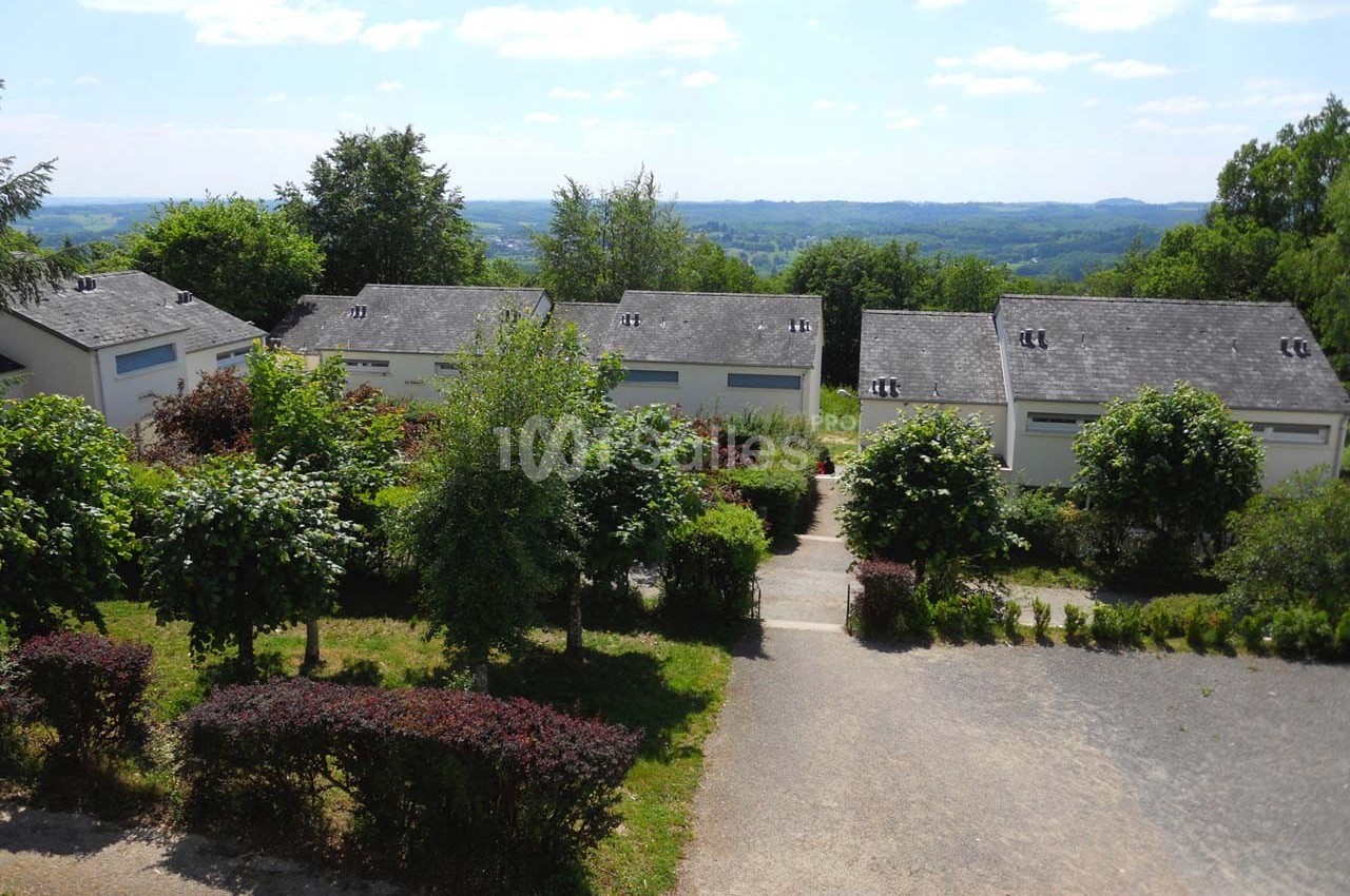 Vue de petites maisons blanches avec toits en ardoise, entourées de végétation, sous un ciel dégagé.