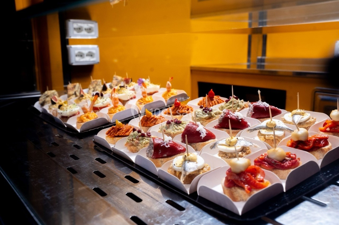 Assortiment de tapas variés présentés sur un comptoir en acier dans un environnement lumineux.