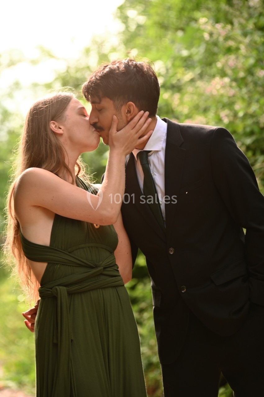 Un couple s'embrasse tendrement dans un environnement naturel verdoyant.