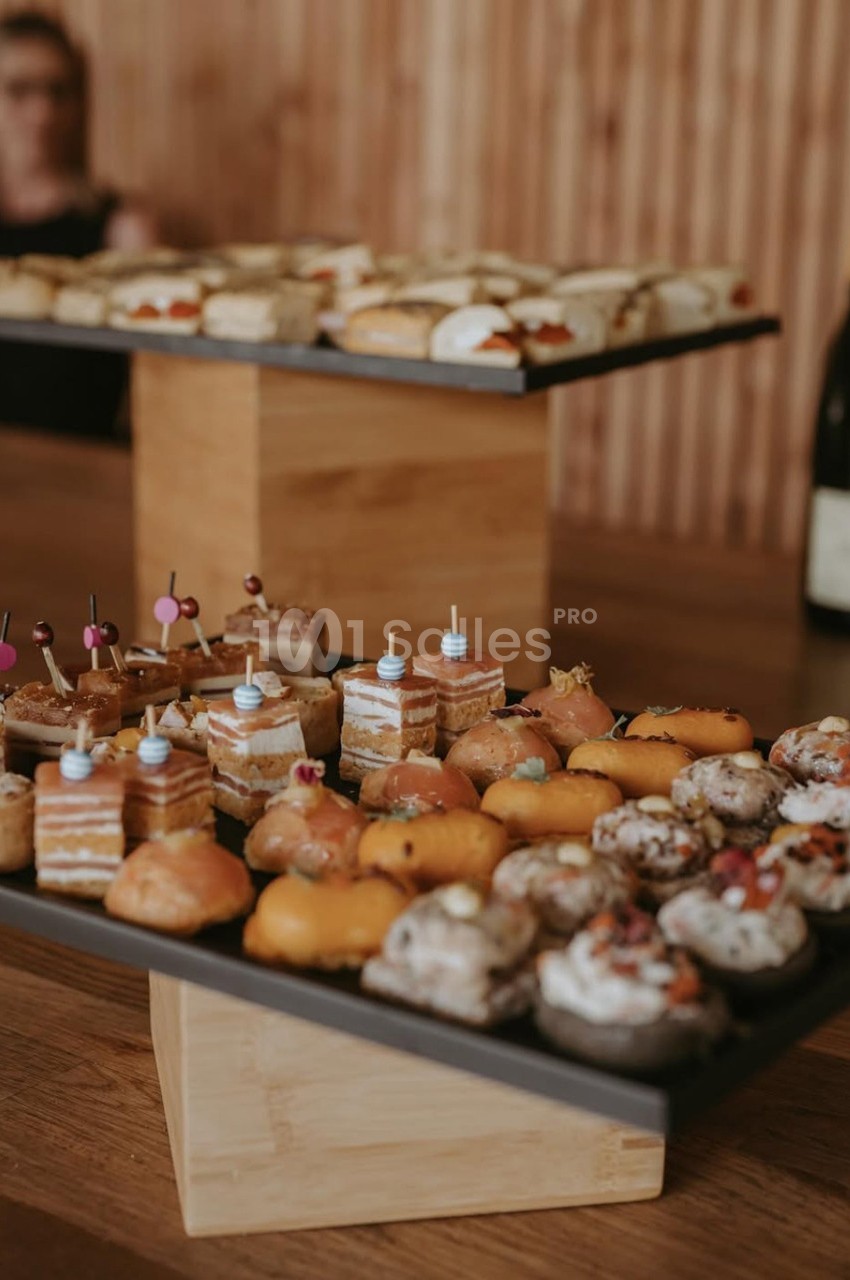 Plateaux de pâtisseries variées et colorées disposés sur une table en bois dans un cadre chaleureux.