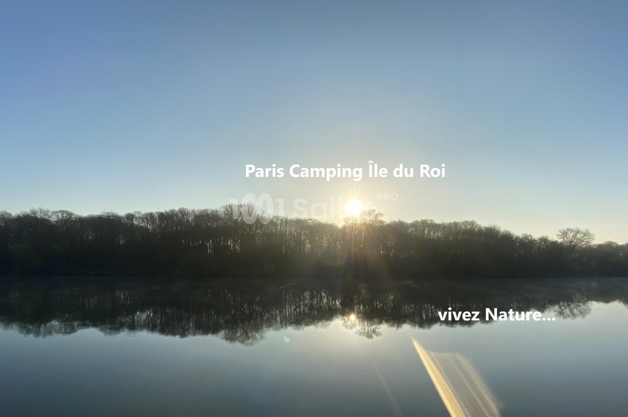 Lever de soleil sur une rivière calme entourée d'arbres, avec un reflet clair dans l'eau.