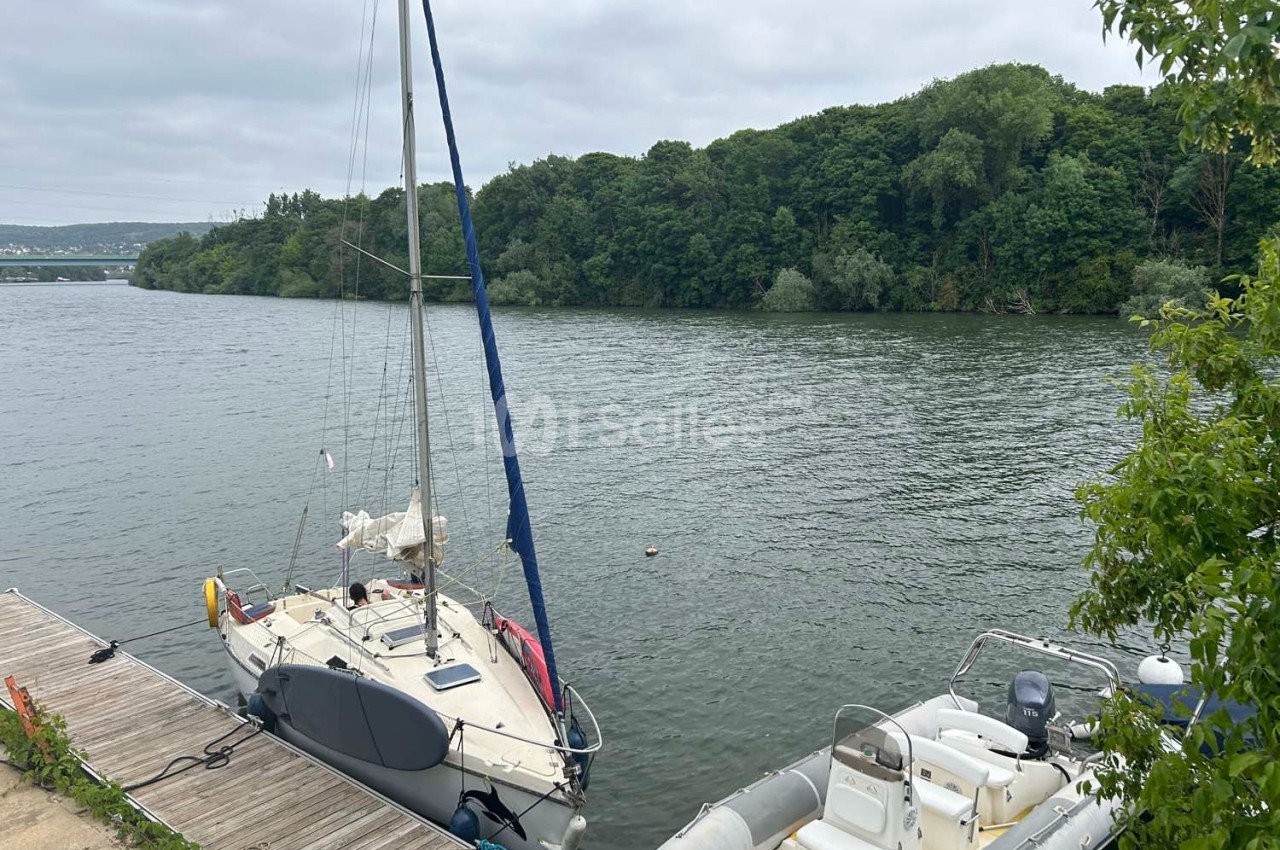 Deux bateaux amarrés à un ponton en bois sur une rivière bordée de végétation dense.
