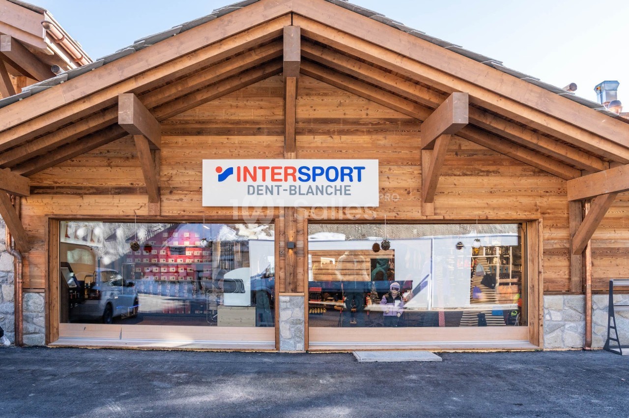 Façade d'un magasin Intersport Dent-Blanche avec une structure en bois et de grandes vitrines.
