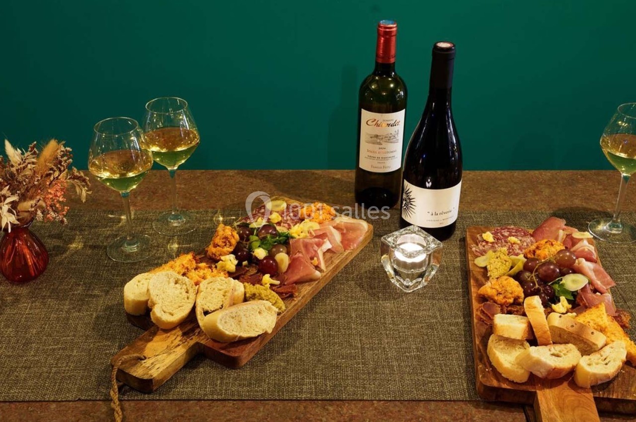 Plateaux de charcuterie et fromage avec pain, accompagnés de verres de vin blanc et rouge sur une table décorée.
