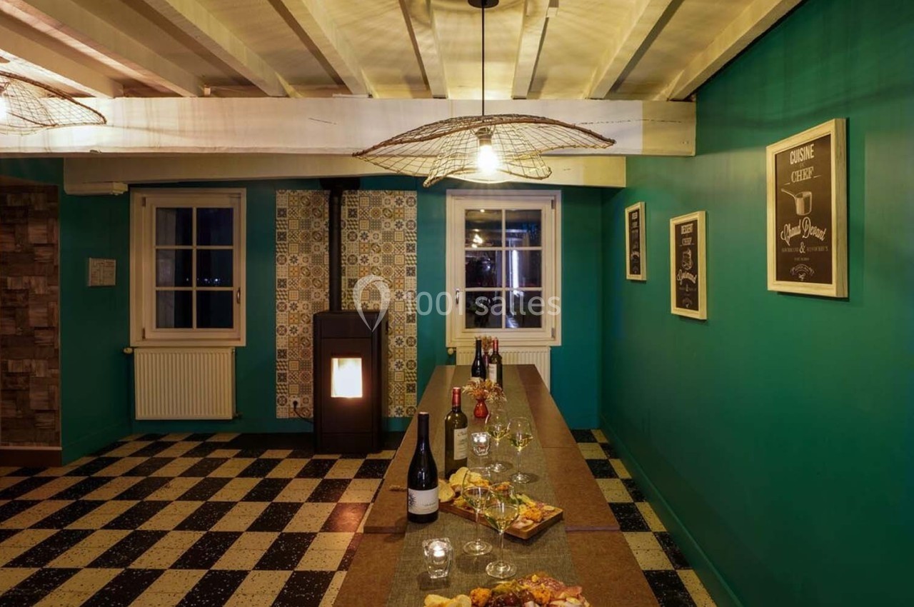 Salle à manger avec un long comptoir, des bouteilles de vin, des amuse-bouches et un poêle à granulés allumé.