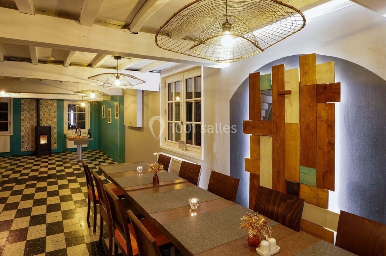 Salle à manger chaleureuse avec longues tables en bois, décor moderne et éclairage suspendu.