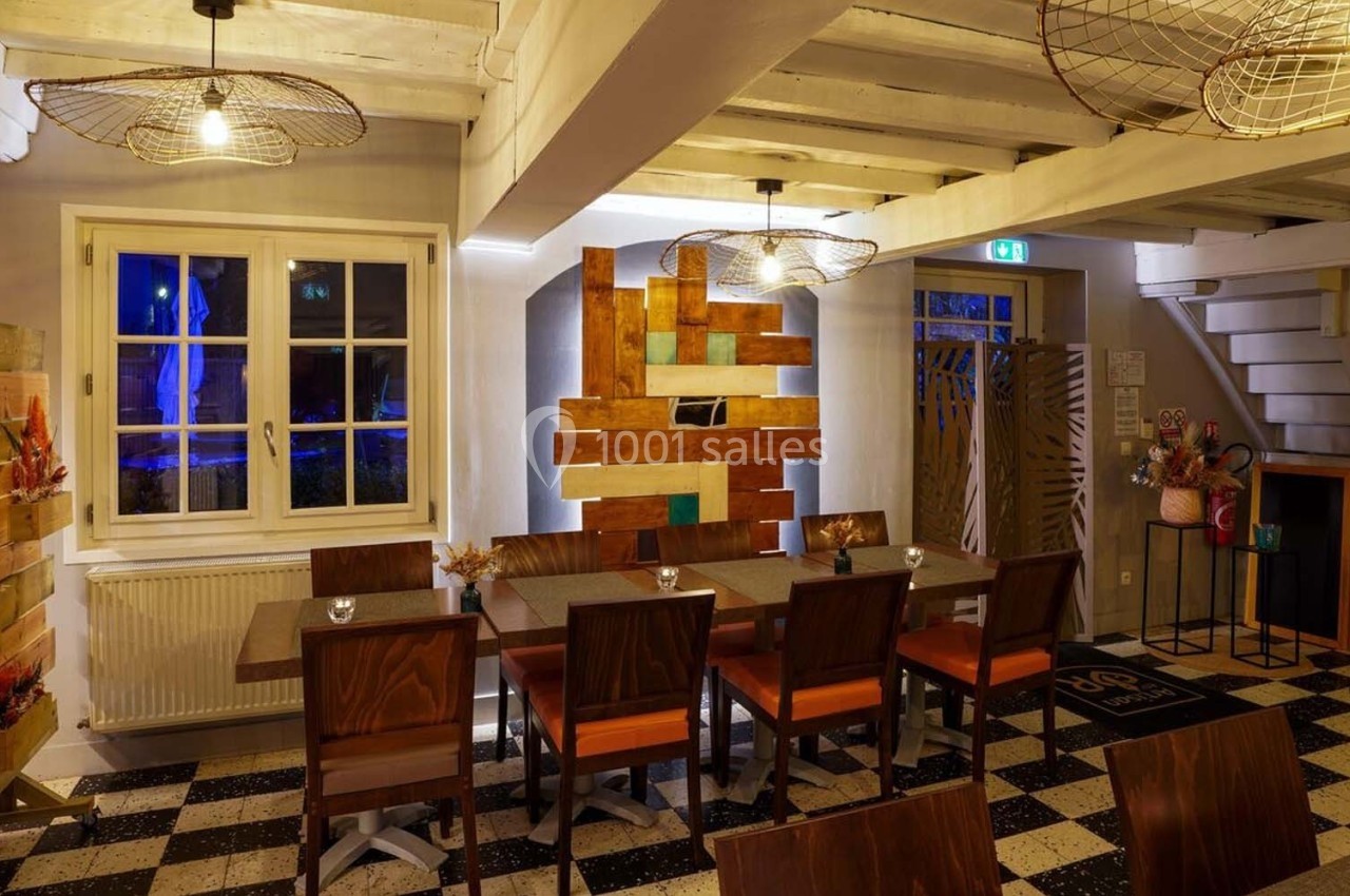 Salle à manger chaleureuse avec tables en bois, chaises assorties, éclairage tamisé et décoration murale colorée.