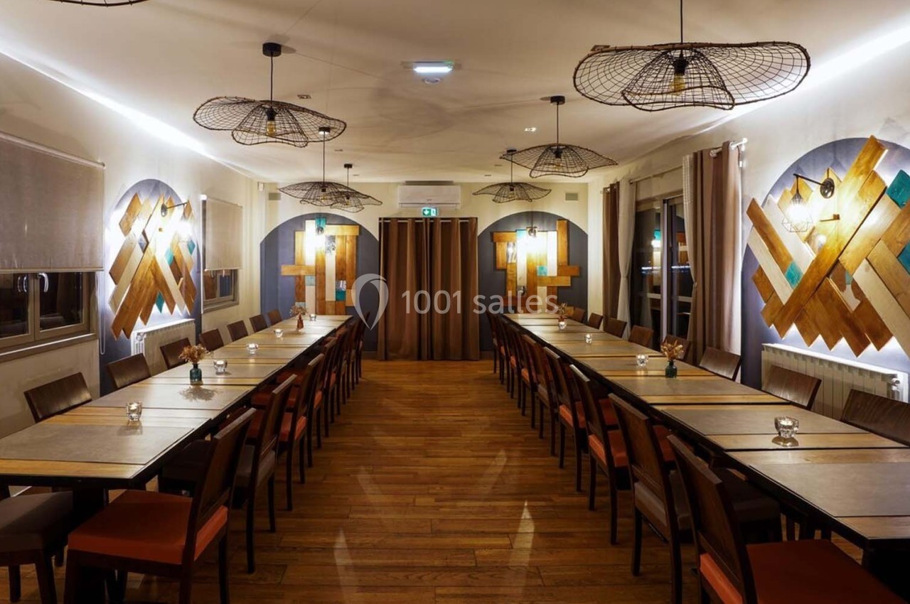 Salle de restaurant lumineuse avec de longues tables alignées, des chaises en bois et des décorations murales géométriques.