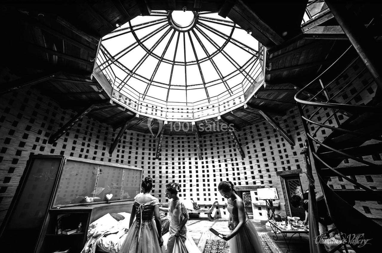 Trois femmes en robes élégantes dans une pièce circulaire avec un plafond en verre et une lumière naturelle.