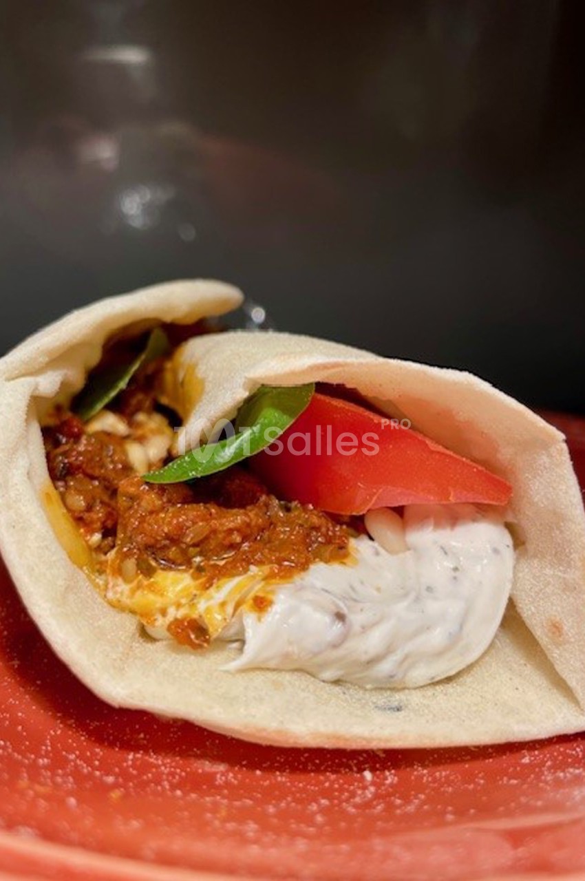 Wrap garni de sauce blanche, tomate, feuilles de basilic et préparation à base de tomates, présenté sur une assiette rouge.
