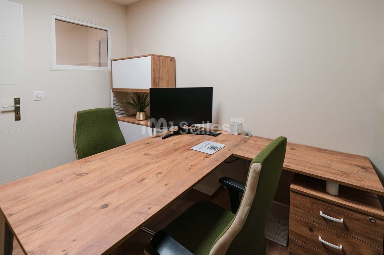 Bureau moderne avec deux chaises, un écran d'ordinateur, un bureau en bois et des rangements dans une pièce lumineuse.