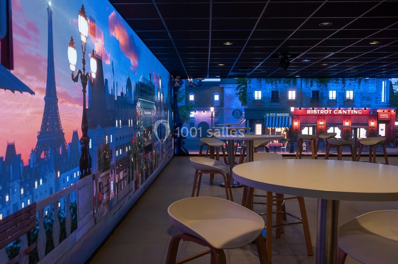 Salle moderne avec tables et chaises, décorée d'une fresque lumineuse représentant une vue parisienne avec la tour Eiffel.