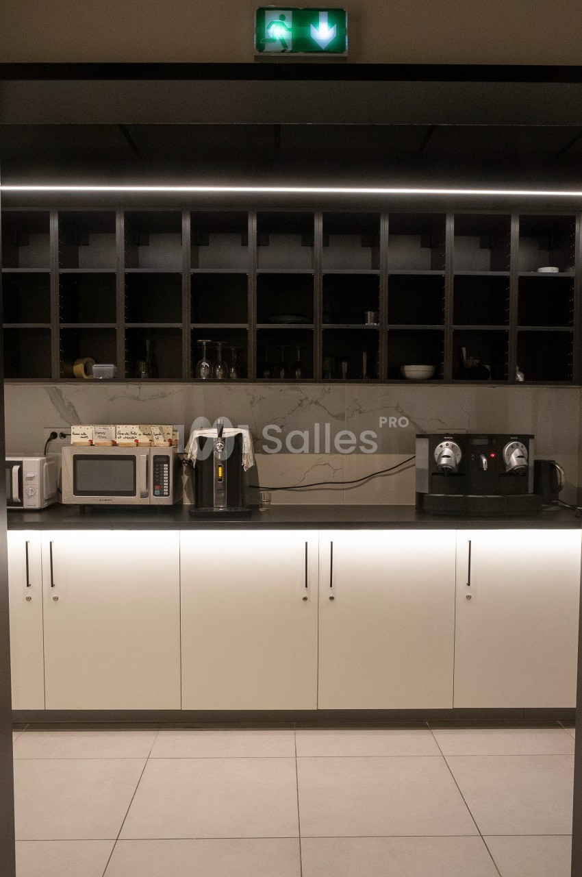 Cuisine moderne avec rangements ouverts, micro-ondes, grille-pain, cafetière et machine à café sur un plan de travail.