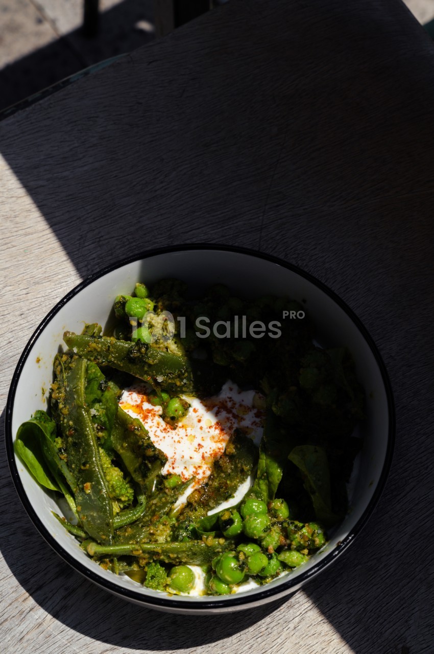 Assiette de pâtes vertes aux légumes frais, sauce pesto et crème, garnie de piment rouge.