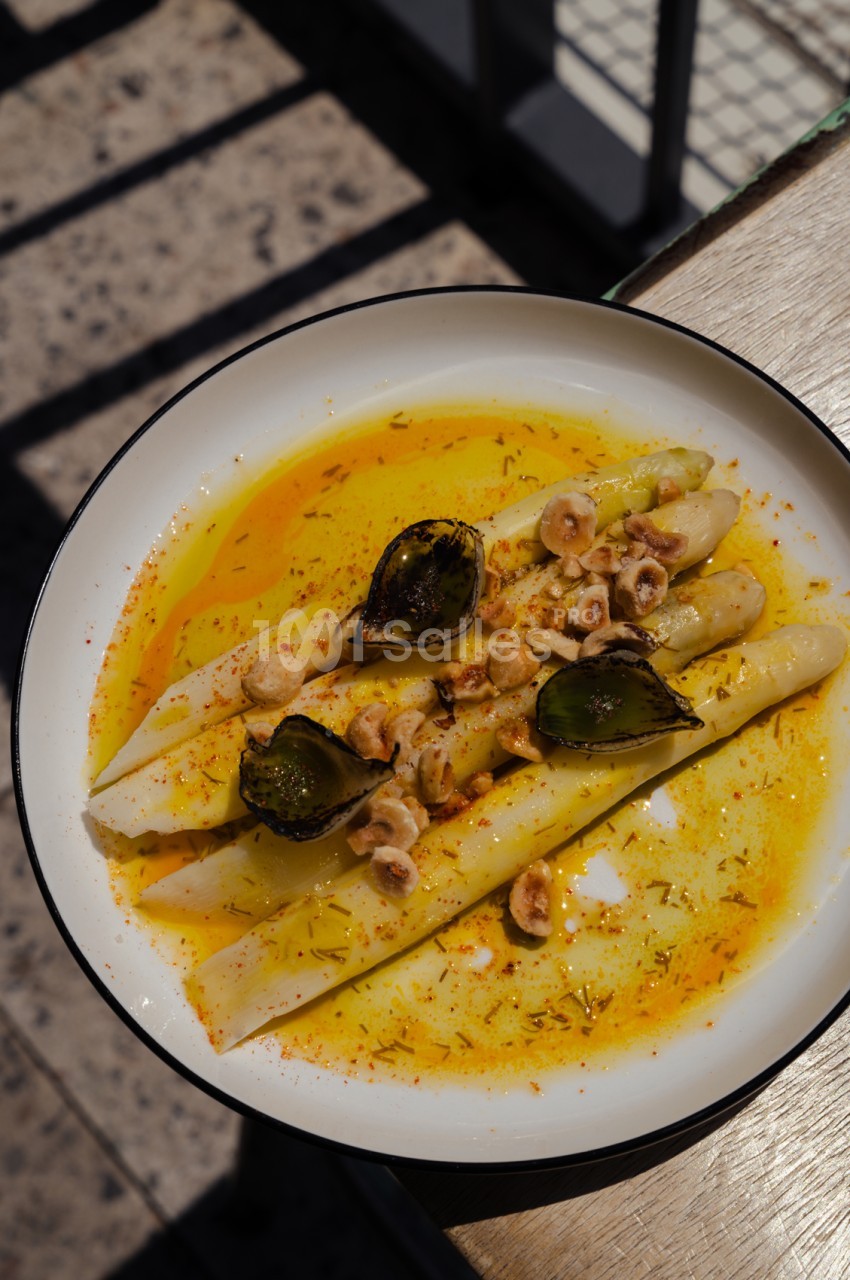 Assiette de calamars et moules en sauce safranée, garnie de piment d'Espelette, en terrasse ensoleillée.
