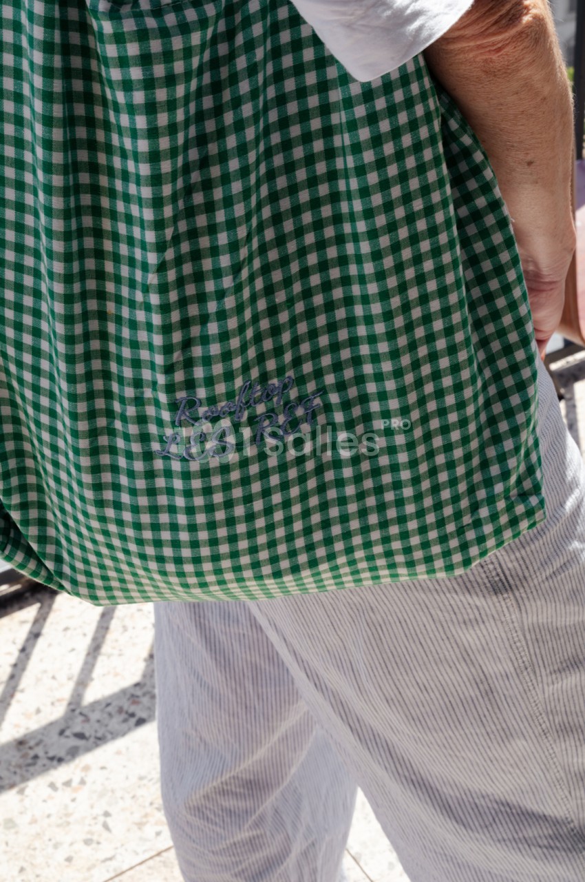 Personne vêtue d'une robe à carreaux vert et blanc en extérieur ensoleillé.