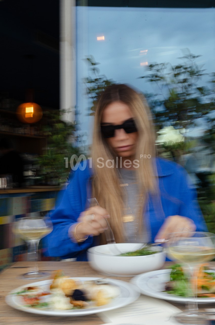 Convive dégustant un plat à une table en terrasse avec vue sur Marseille en fin d'après-midi.