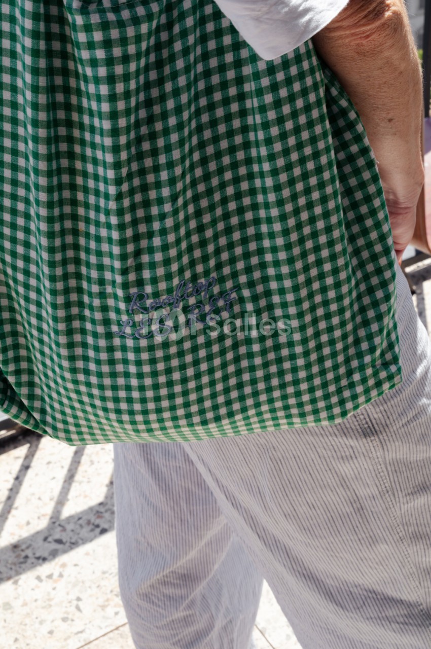 Personne vêtue d'une robe à carreaux vert et blanc en extérieur ensoleillé.