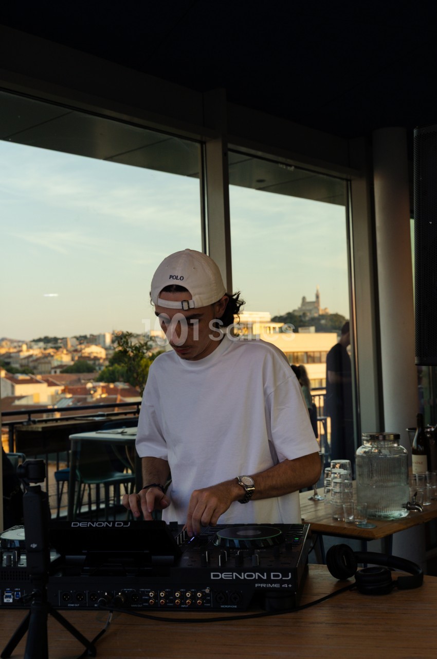 DJ en terrasse sur rooftop avec vue panoramique sur la ville de Marseille en arrière-plan.