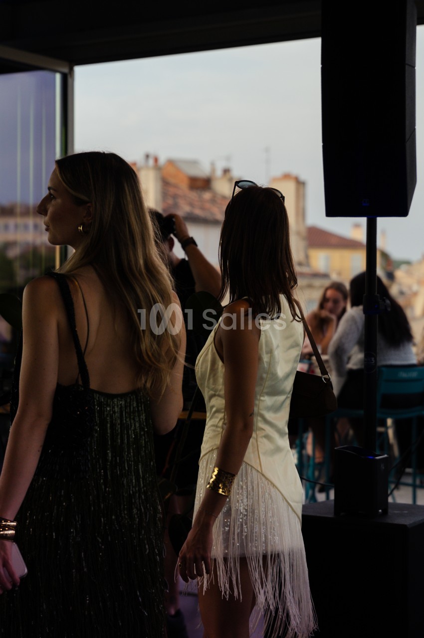 Intérieur d'une salle avec vue sur les toits de Marseille - convives debout face aux baies vitrées.