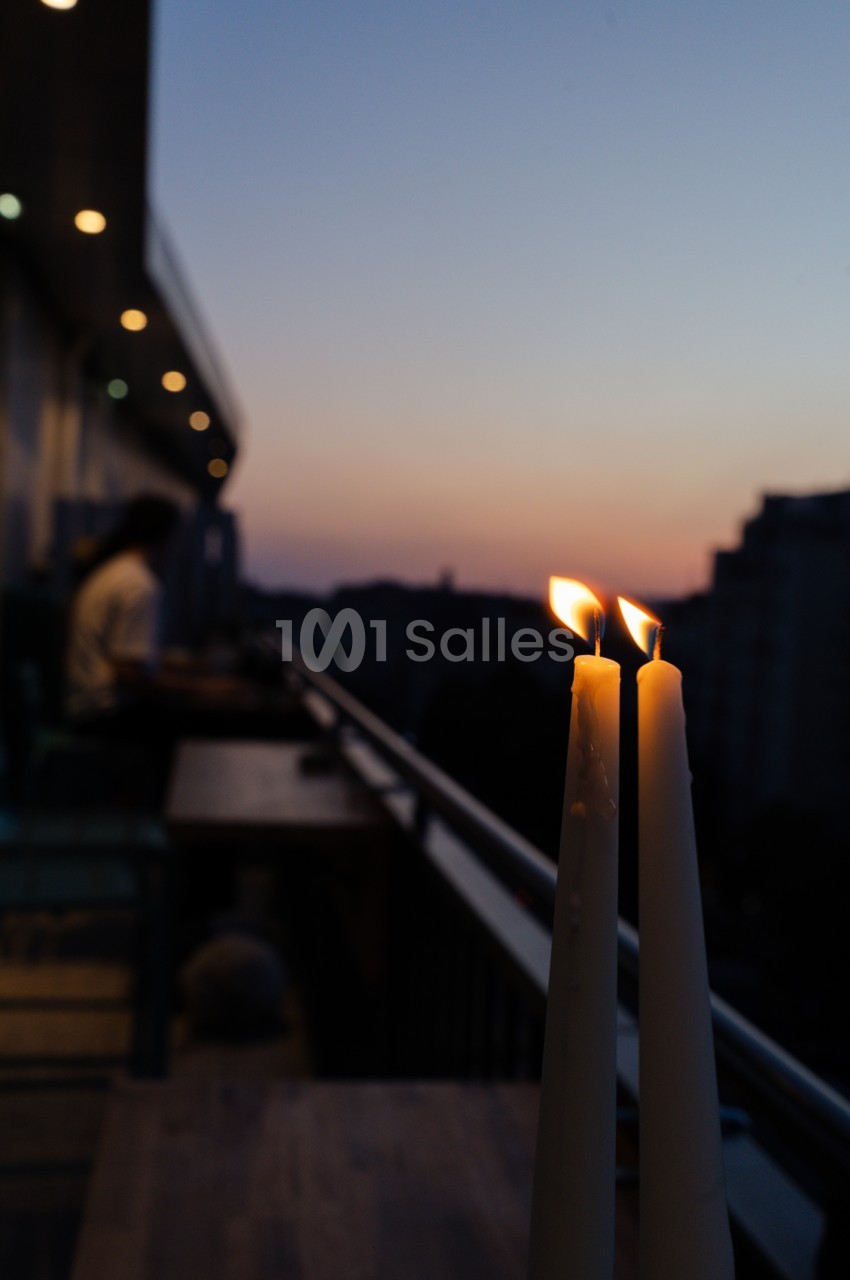 Deux bougies allumées sur terrasse avec vue crépusculaire sur Marseille au coucher de soleil.