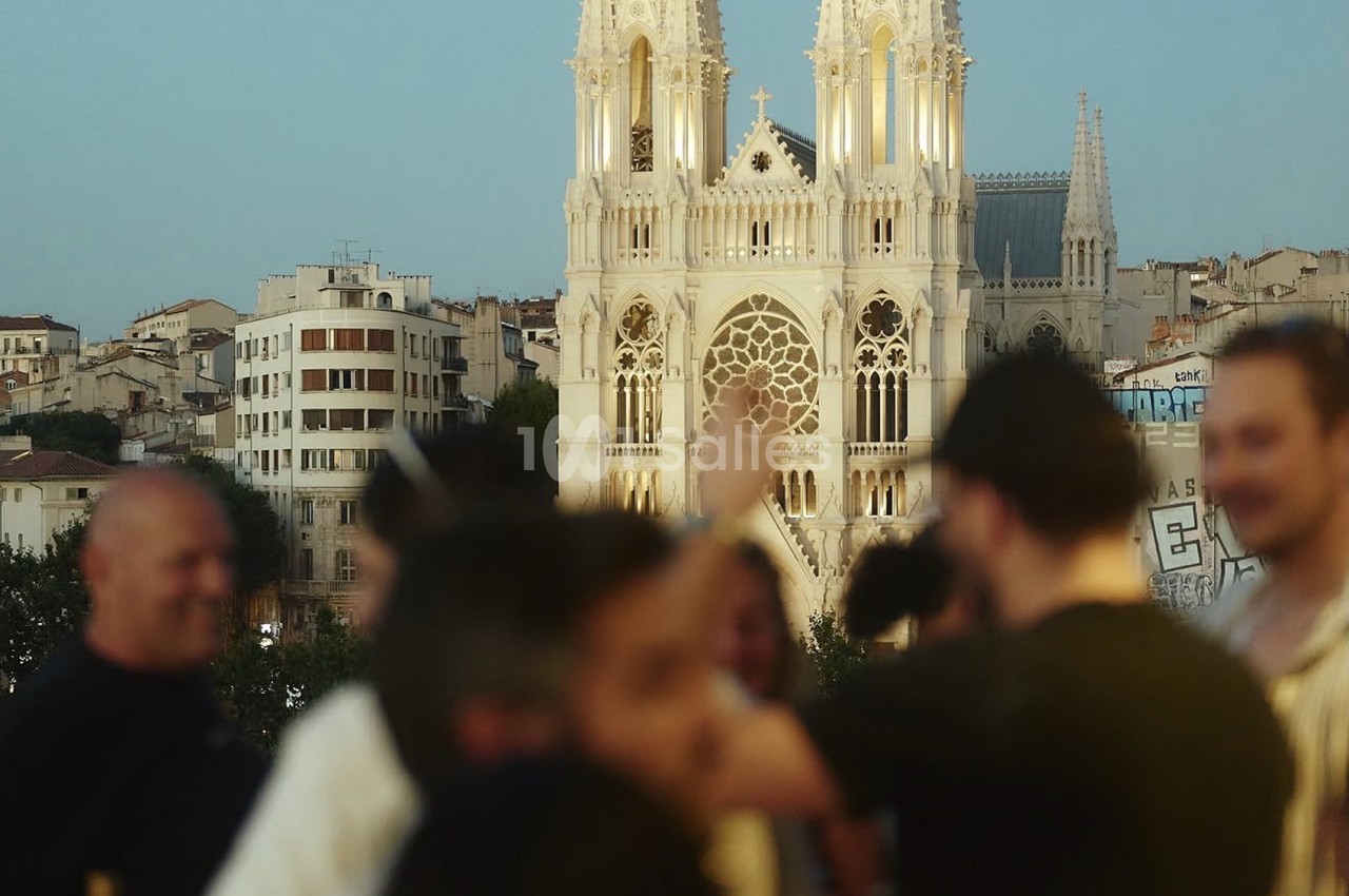 Plusieurs personnes en premier plan flou face à une cathédrale gothique blanche en arrière-plan.