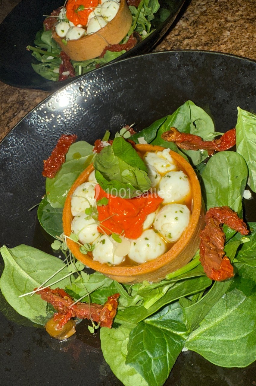 Tartelette garnie de billes de fromage, sauce rouge, sur un lit de jeunes pousses et tomates séchées.