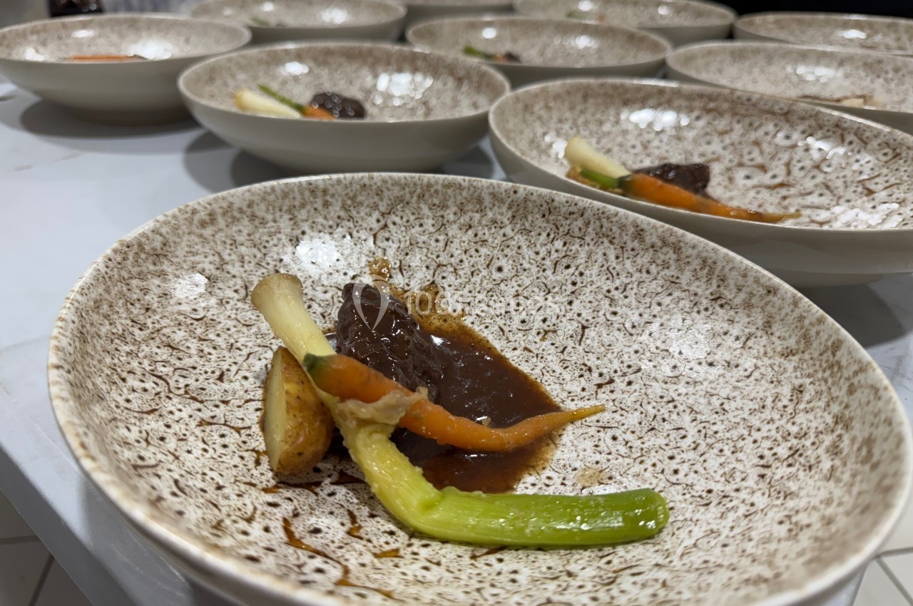 Assiette en céramique contenant un plat composé de légumes et d'une sauce brune, disposée sur une table.