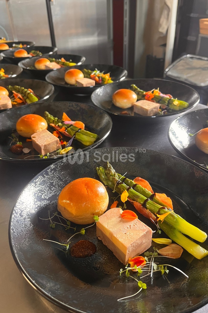 Assiette gastronomique avec foie gras, asperges, pain brioché et garnitures colorées, dressée pour un service en série.