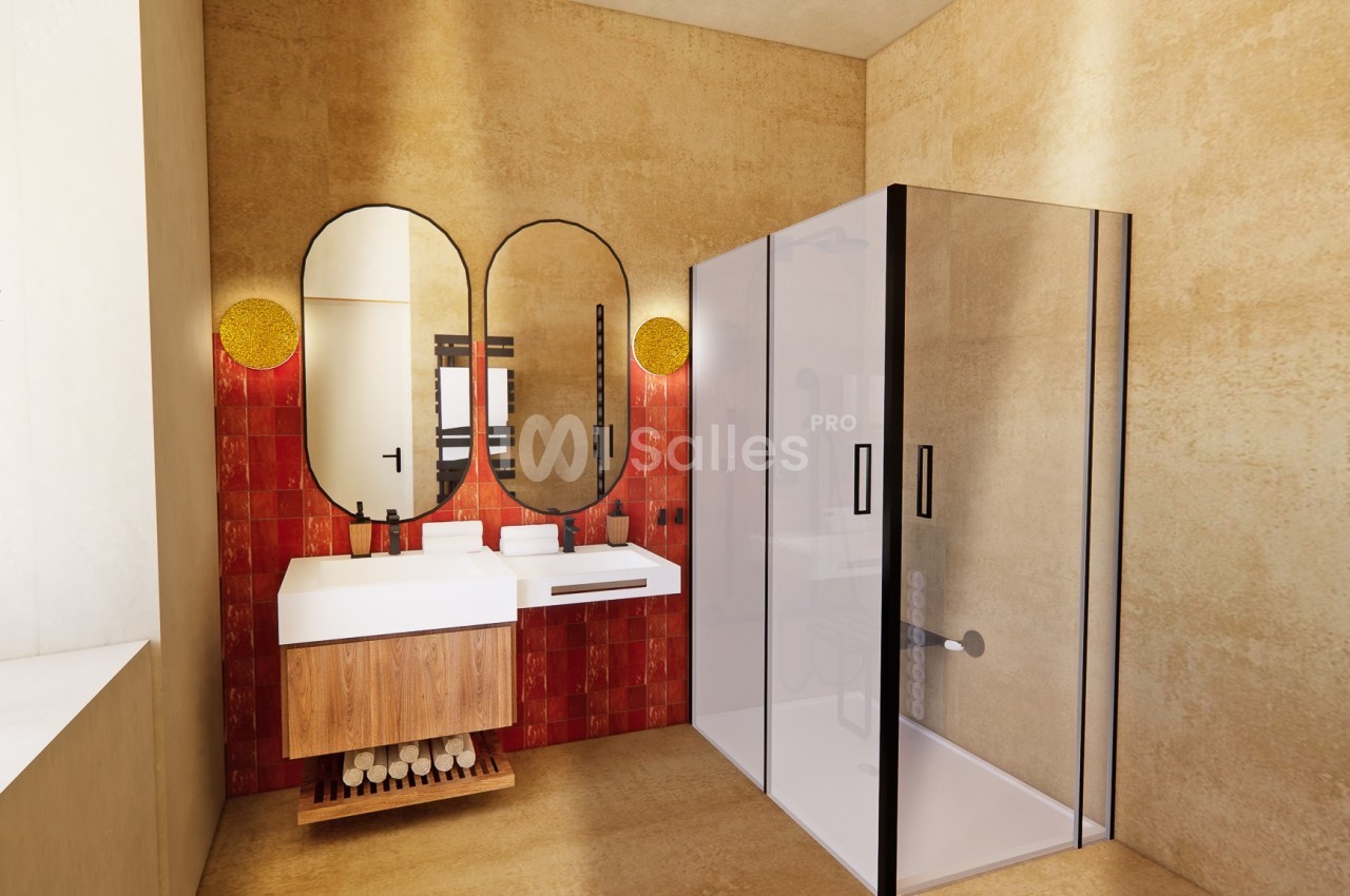 Salle de bain moderne avec double vasque, miroirs ovales, douche vitrée et murs beige et rouge.