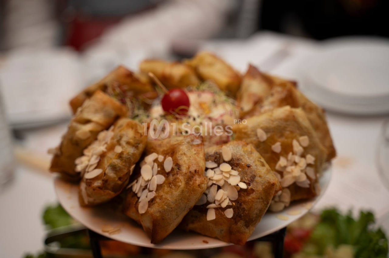 Assortiment de feuilletés dorés garnis, décorés d'amandes effilées et d'une tomate cerise au centre.