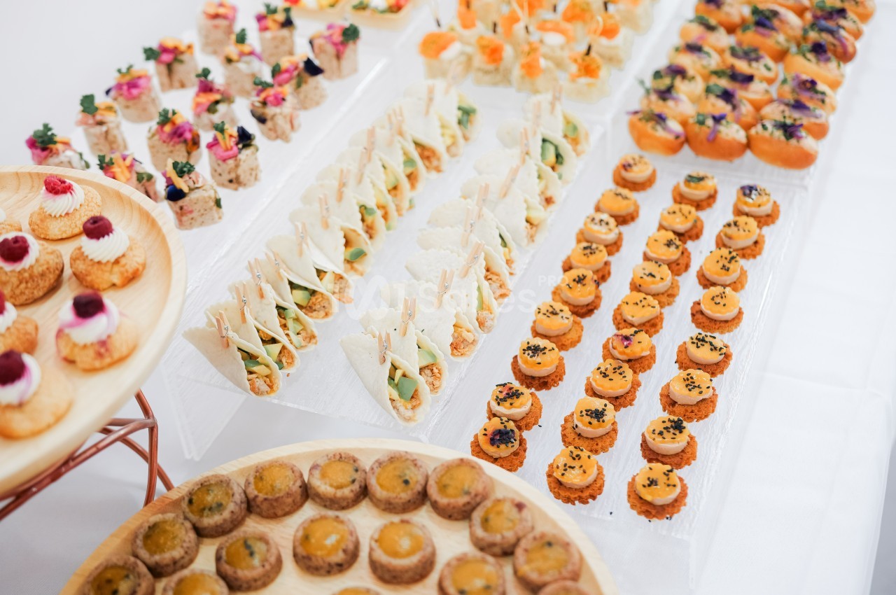 Plateau de canapés variés disposés sur des présentoirs, comprenant des bouchées salées et colorées.