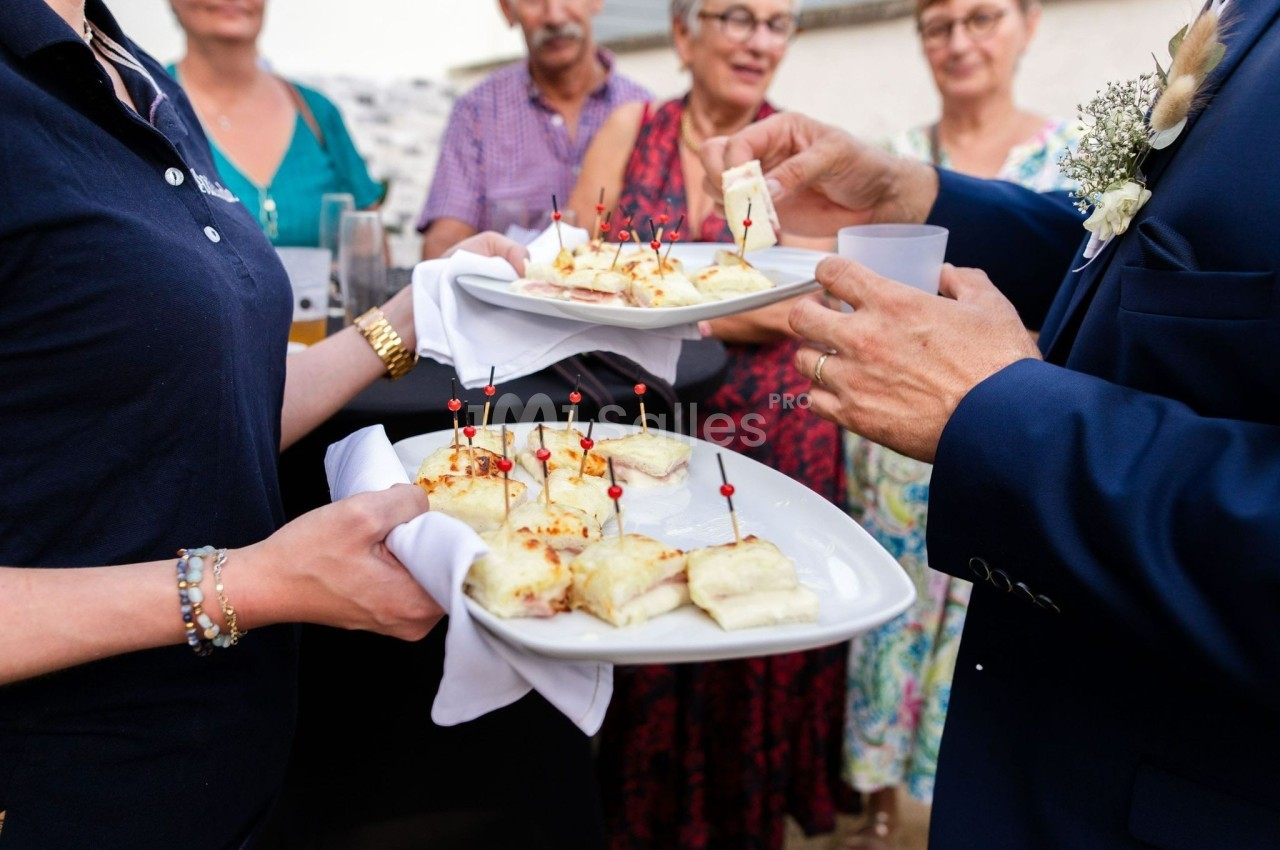 Des plateaux de bouchées apéritives sont servis à des invités lors d'un événement en plein air.