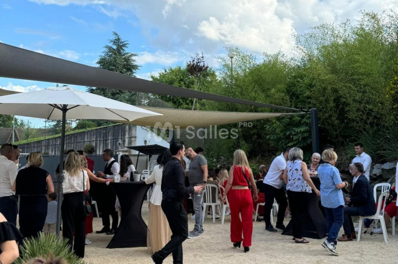 Groupe de personnes discutant et partageant un moment convivial dans un espace extérieur ombragé.