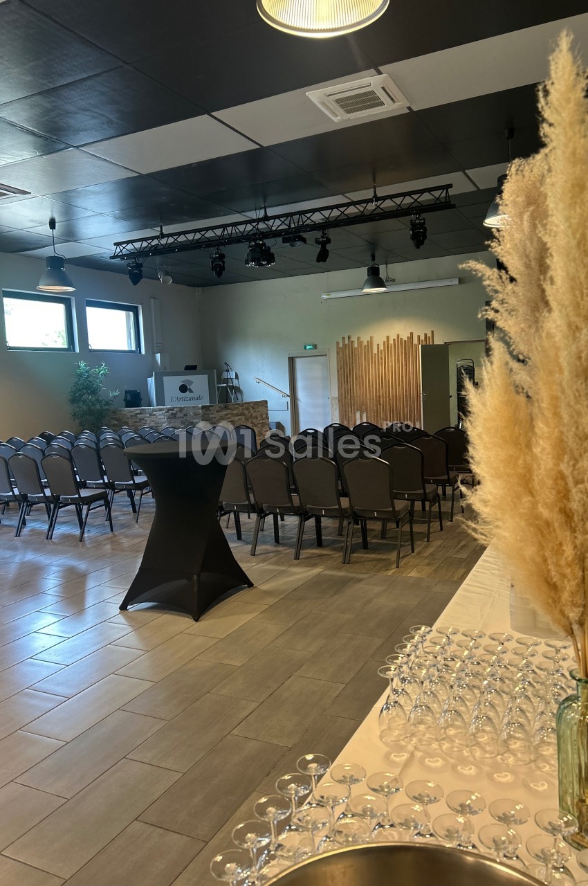 Salle de réception aménagée avec des rangées de chaises, une table de verre et une décoration en herbes séchées.