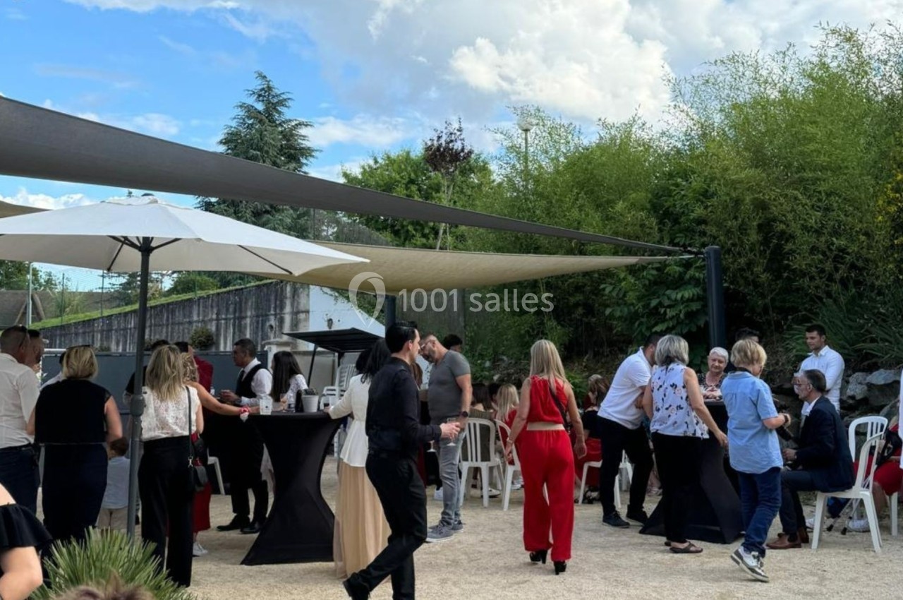 Groupe de personnes discutant et partageant un moment convivial dans un espace extérieur ombragé.